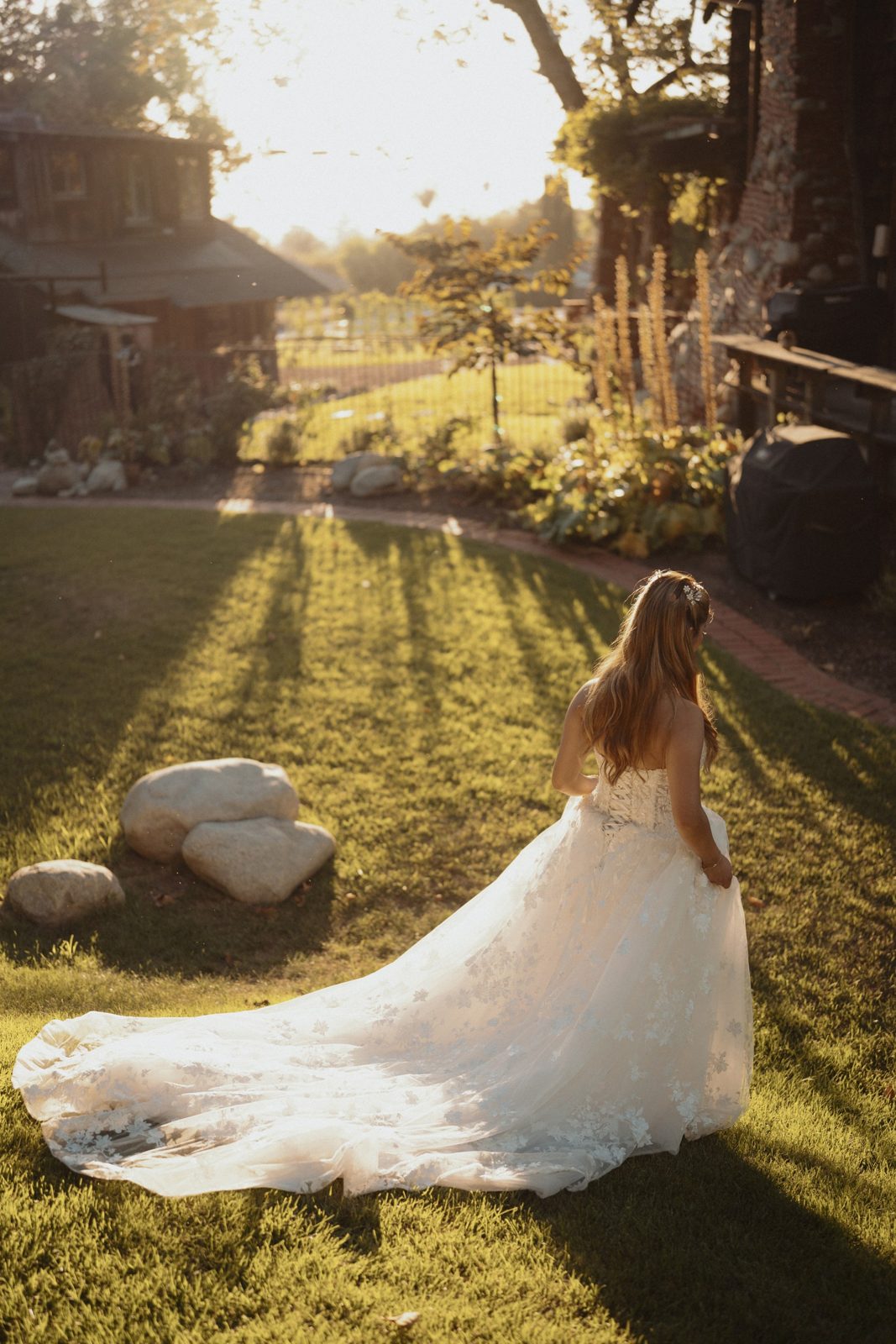 Bride in a lace gown walking across the lawn at golden hour
