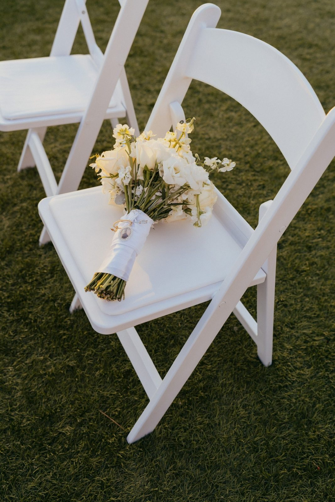 Bridal bouquet resting on a white ceremony chair
